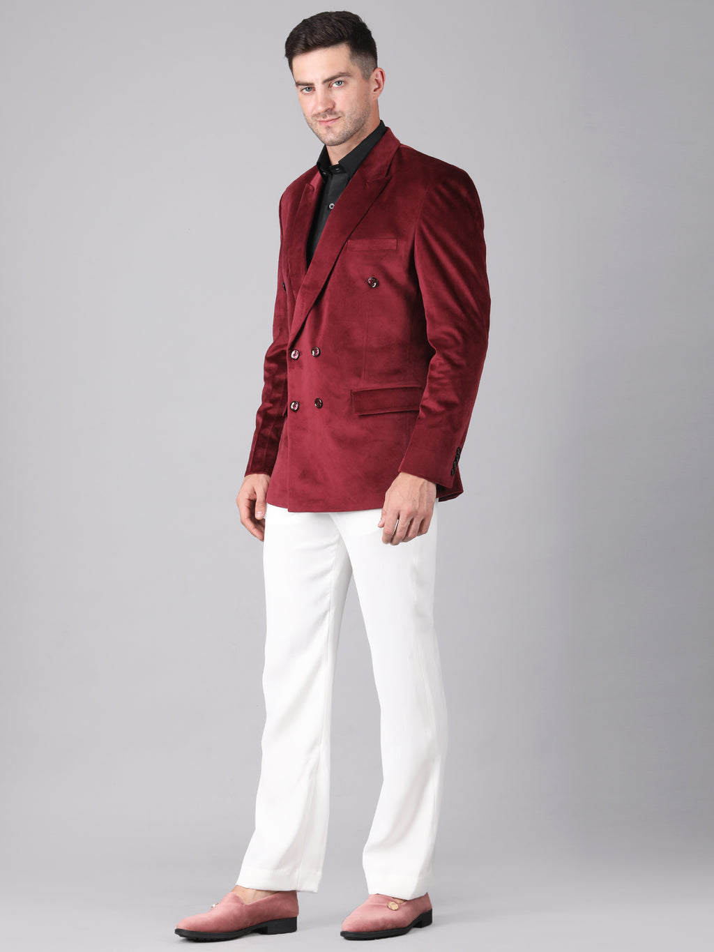 Man wearing a burgundy blazer and white pants on a gray background