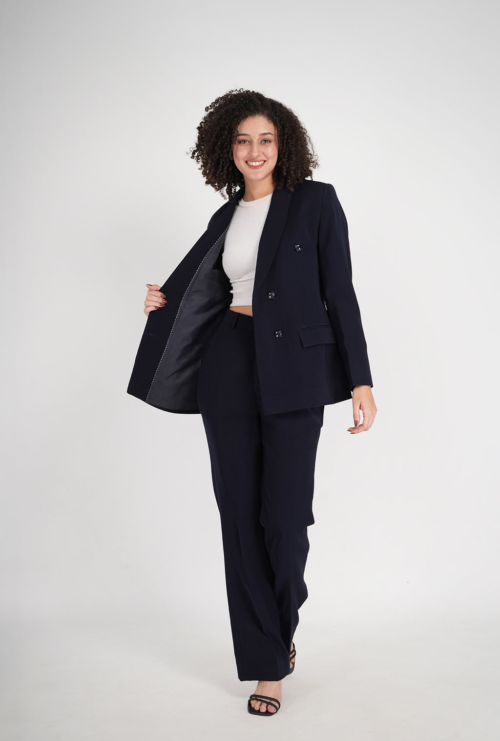 Woman wearing a navy suit with a white top on a white background
