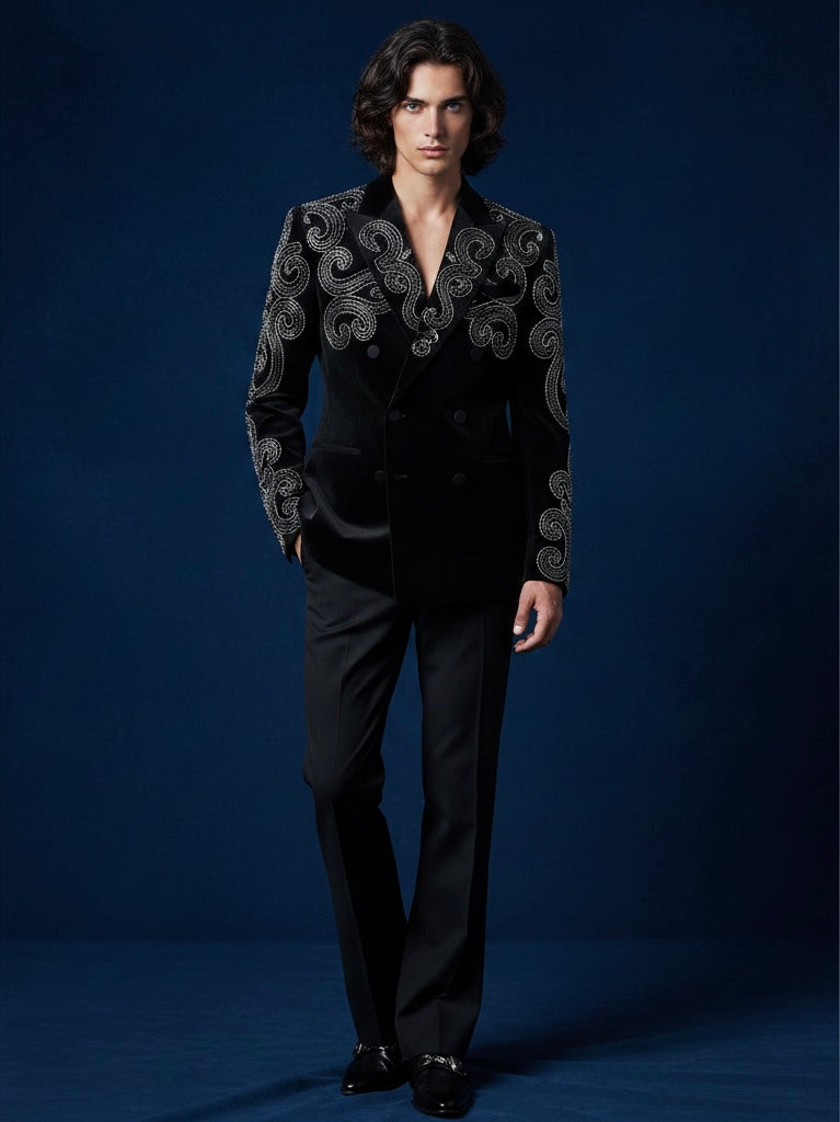 Man wearing a black suit with intricate embroidery on a blue background