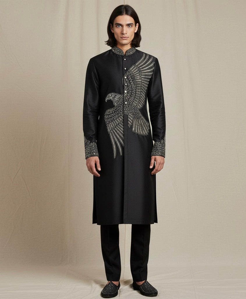 Man wearing a black embroidered kurta with silver details on a beige background