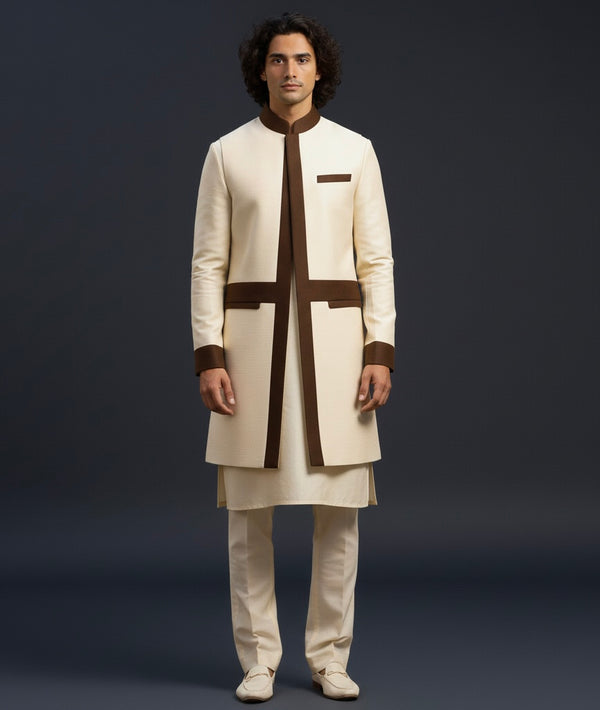 Man wearing a traditional cream and brown kurta against a dark background