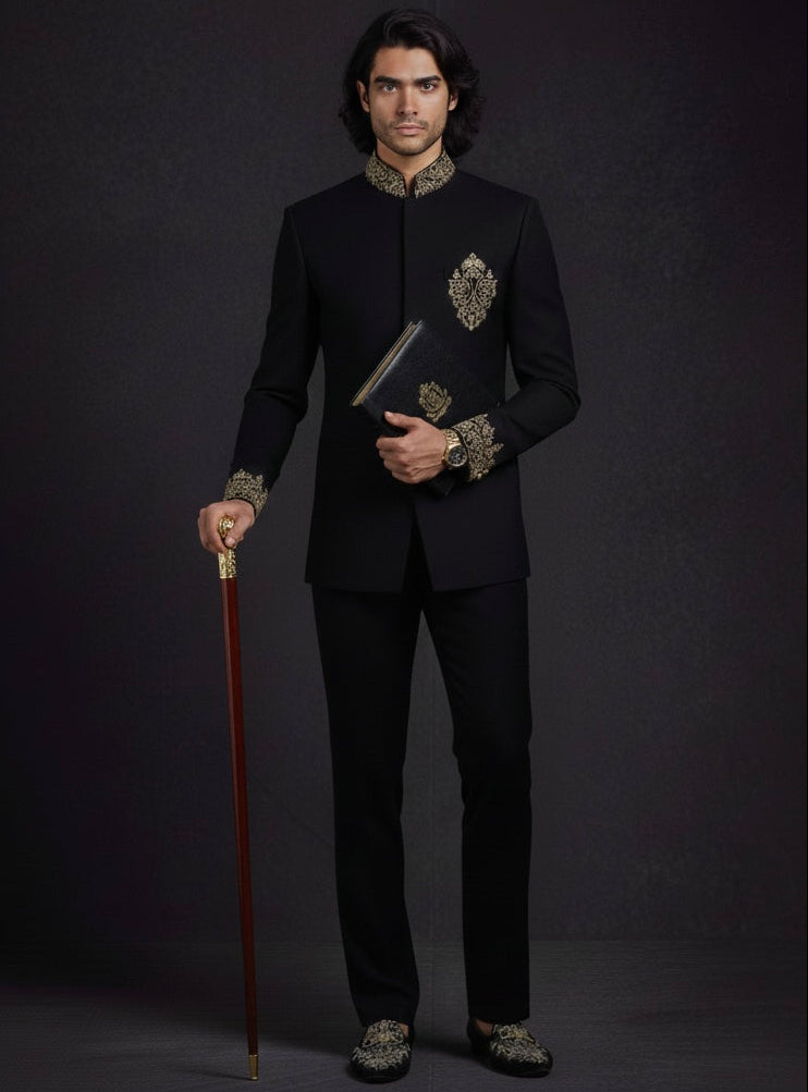 Man in a black embroidered suit holding a cane against a dark background