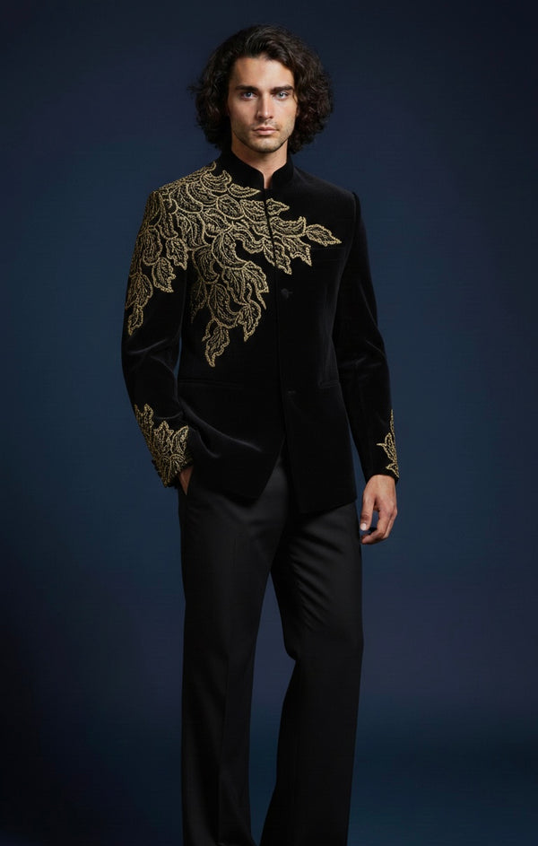 Man wearing a black outfit with gold embroidery against a dark background