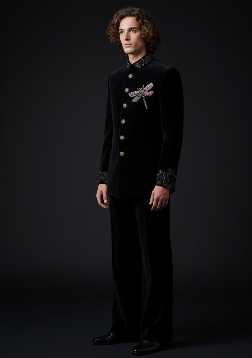 Man wearing a black suit with dragonfly embroidery on a dark background