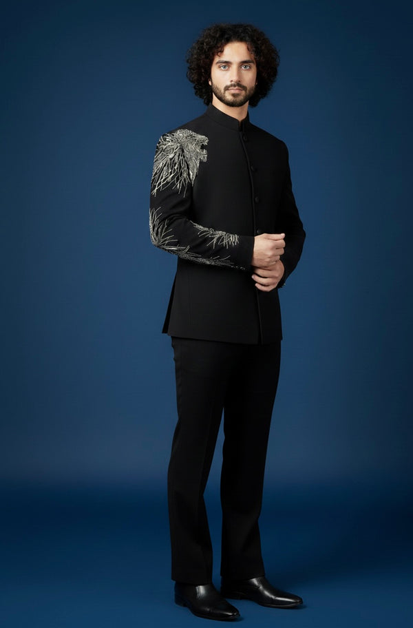 Man wearing a black suit with decorative arm details against a blue background