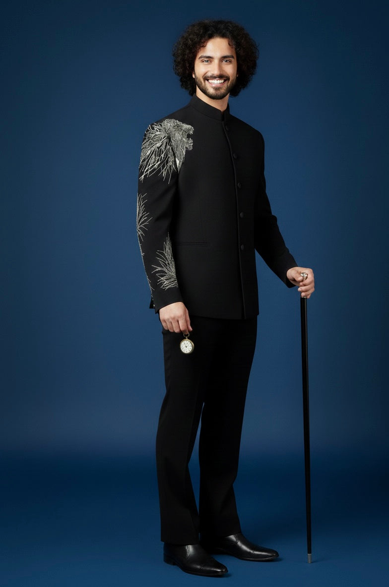 Man in a black suit with a patterned sleeve holding a cane against a blue background