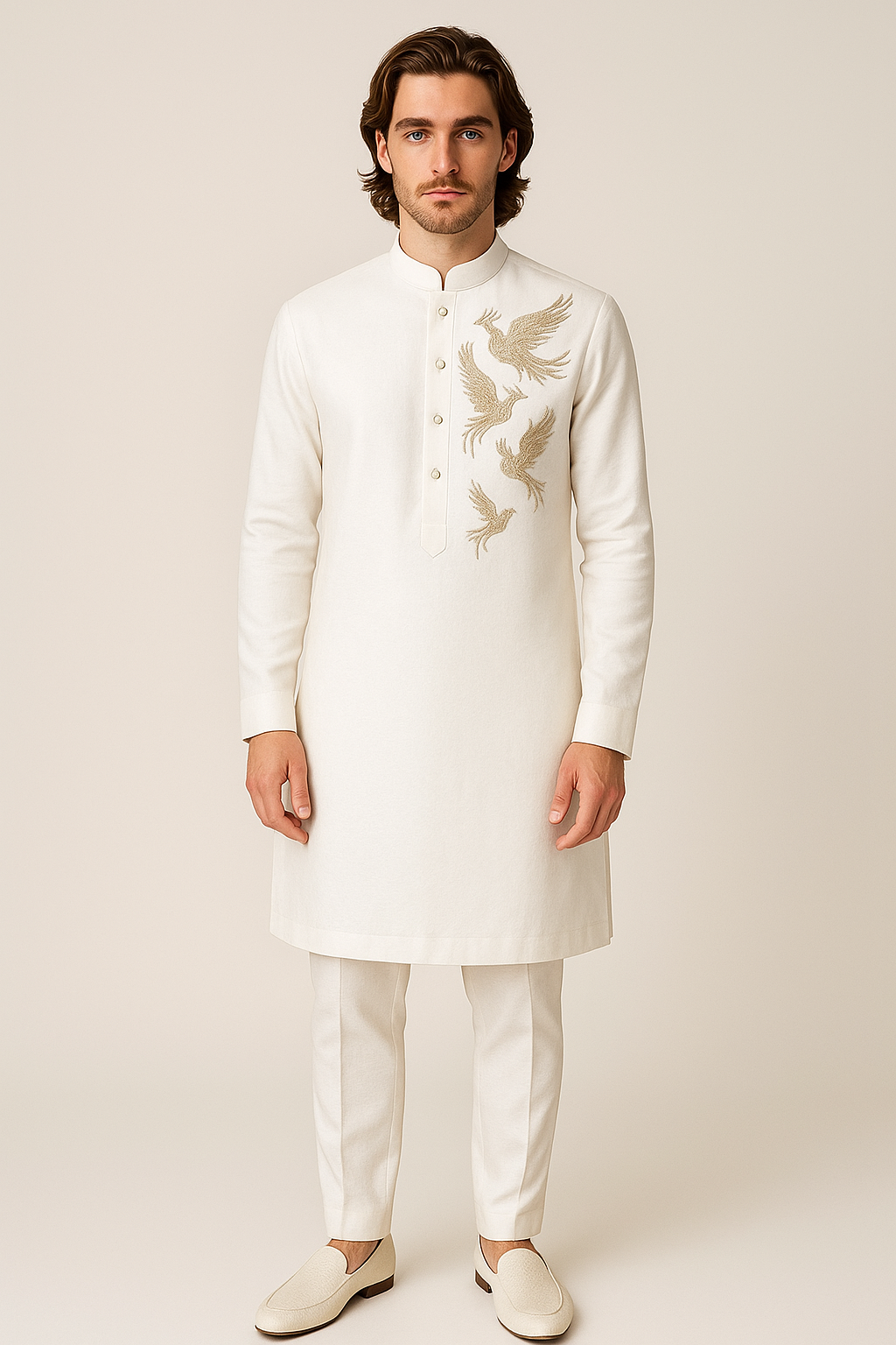 Man wearing a white embroidered kurta with pants on a plain background