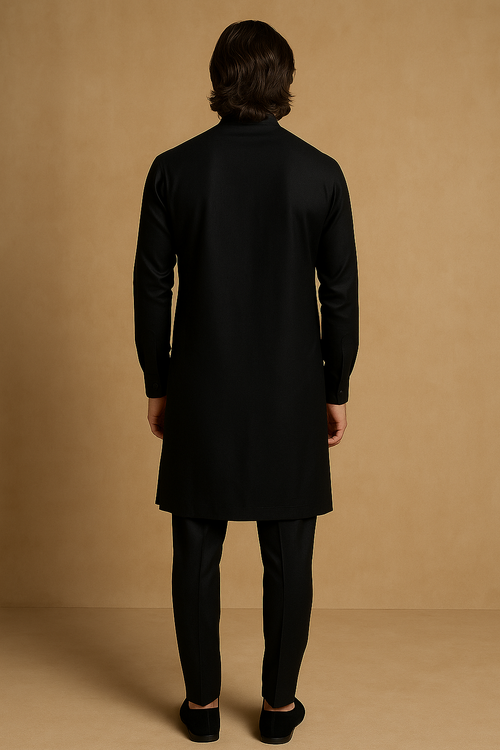 Person wearing a black coat and pants against a beige background