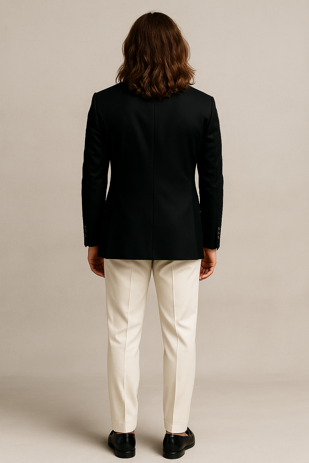 Person wearing a black blazer and white pants on a beige background